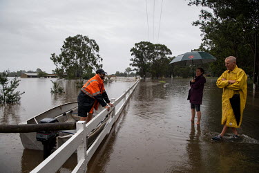A man in a boat talks to a couple standing in flood water in Windsor where over the previous weekend, the Hawkesbury River rose rapidly by more than 30 feet.