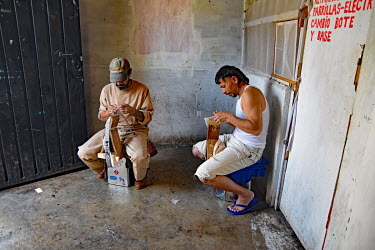 Inmates making leather belts in a prison workshop where prisoners make artisanal products for sale.
