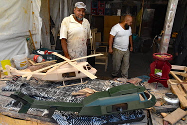 An inmate with a hand made wooden helicopter gunship, manufactured in a prison workshop where prisoners make various artisanal products for sale.