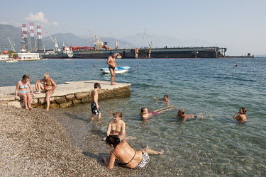 Locals relax on the beach of Bijela, near an industrial site and ship yard in the Bay of Kotor (Boka Kotorska), a winding bay on the Adriatic Sea, sometimes called Europe's southernmost fjord.