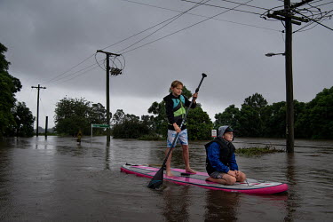 Two boys on a paddle board make their way along the flooded streets in Windsor where over the previous weekend, the Hawkesbury River rose rapidly by more than 30 feet.