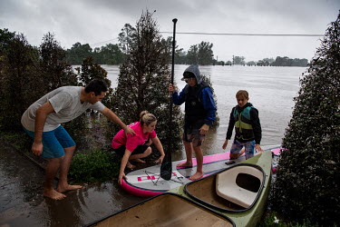 Two boys on a paddle board land at the edge of a flooded road in Windsor where over the previous weekend, the Hawkesbury River rose rapidly by more than 30 feet.