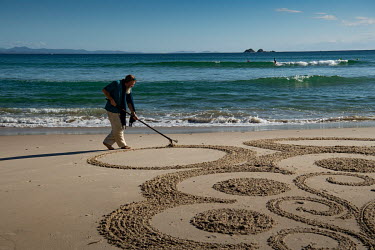 An artist on the beach who says he has been making sand art since 1997.  The Byron Bay community is at war with a proposed Netflix reality TV show called Byron Baes, which locals feel does not represe...