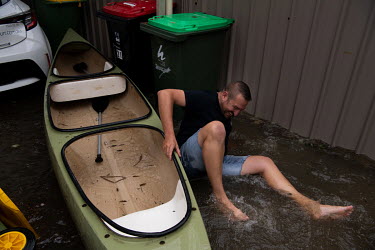 A man slips as he tries to take a canoe onto the flooded streets in Windsor where over the previous weekend, the Hawkesbury River rose rapidly by more than 30 feet.