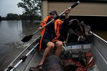 Shawn Johnson paddles his aluminium boat after saving riding sadles and car parts from his shed that is mostly underwater after the Hawkesbury River rose rapidly by more than 30 feet over the previous...