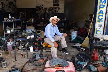 A man who repairs generator and electric tools sits in his shop.