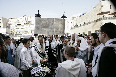 A man holds up a Torah scroll as Orthodox Jews pray at the Wailing Wall during Passover.