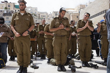 Israeli Defence Force soldiers, their weapons laid on the ground beside them, praying at the Wailing Wall during Passover.