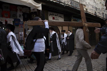 A group of Orthodox Jews pass two Christian women carrying a large wooden cross along the Via Dolorosa during Passover/Easter.
