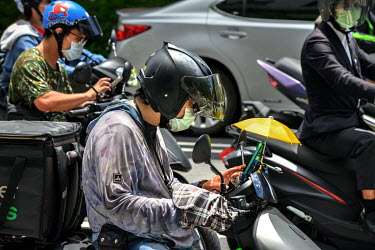 Food delivery riders checking their phones for orders while stopped at a junction in central Taipei where meal delivery services such as Food Panda and Uber Eats have seen a boom in demand ever since...