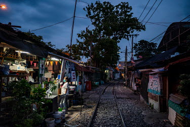 Residents of the Klong Toei slum community who live along the railway tracks gather at dusk.
