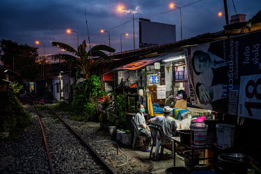 Residents of the Klong Toei slum community who live along the railway tracks gather at dusk.