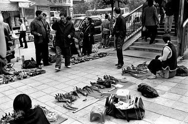 Tibetan migrants selling animal parts from street stalls lining a busy pavement.