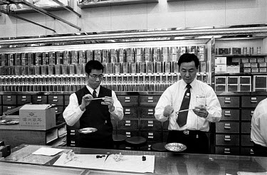 Inside a Hong Kong chemist, shop assistants preparing a prescription for a cold and flu which contains bear bile for the customer, a wealthy Hong Kong resident.