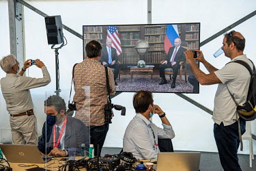 Members of the world's press watch a television broadcast from the media centre set up at the Joe Biden/Vladimir Putin summit meeting which was taking place at nearby Villa La Grange.