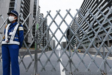 A security stands in front of a gate at the Olympic and Paralympic Village for the delayed Tokyo 2020 Games, constructed in the Harumi waterfront district.