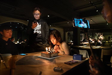 Nai Nai, a 23-year-old live-streamer, blows out the candles on her birthday cake as her male fans who were attending her party watch her on their smartphones. Nai Nai's fans are mostly Chinese men bet...
