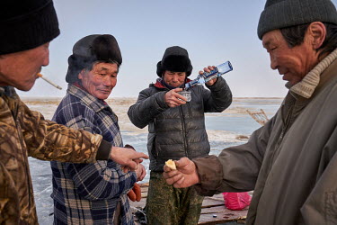 Buryati ice fishermen in Selenga drink and eat while catching fish using horses on the ice of Lake Baikal.   Crowned the 'Jewel of Siberia', Lake Baikal is the world's deepest lake, and the biggest la...