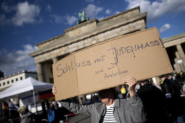 A protestor with a sign that reads 'Stop hating Jews and hating Arabs' during a rally of the German Jewish community and political parties in front of the Brandenburger Gate in solidarity with Israel...