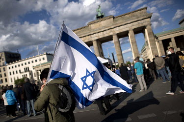 A protestor with the flag of Israel during a rally of the German Jewish community and political parties in front of the Brandenburger Gate in solidarity with Israel and against anti-semitism and racis...