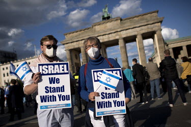 Protestors with the flag of Israel and placards that read: 'Israel we stand with you' during a rally of the German Jewish community and political parties in front of the Brandenburger Gate in solidari...