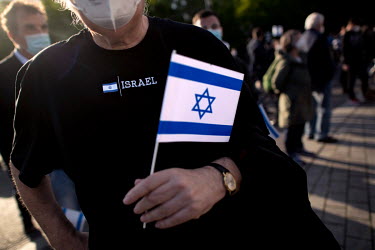 A protestor with the flag of Israel during a rally of the German Jewish community and political parties in front of the Brandenburger Gate in solidarity with Israel and against anti-semitism and racis...