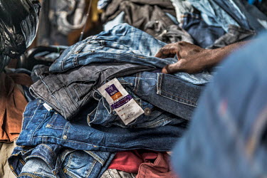 A customer looks through racks of second-hand clothes, many with the price labels of the United Kingdom charity shops they were once on sale in still attached, on stall in Kantamanto market, West Afri...
