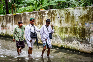 Three blind men follow each other along a flooded road.   Water is essential for survival, yet in Bangladesh water also has the power to destroy anything in its path. For months at a time, monsoon sea...