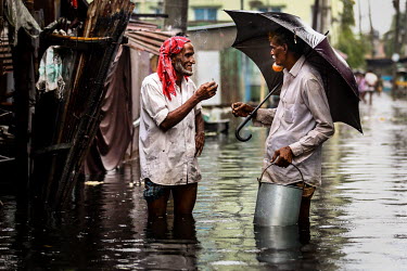Two men share a cigarette while standing in a flooded street.  Water is essential for survival, yet in Bangladesh water also has the power to destroy anything in its path. For months at a time, monsoo...