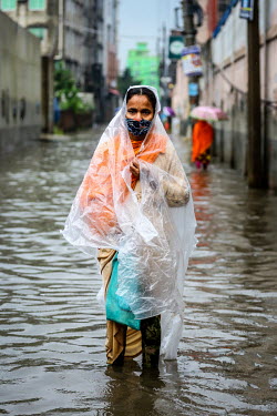 A woman wades along a street through calf deep flood water.  Water is essential for survival, yet in Bangladesh water also has the power to destroy anything in its path. For months at a time, monsoon...