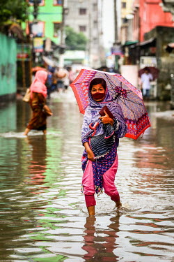 A woman walks along a street through calf deep flood water.  Water is essential for survival, yet in Bangladesh water also has the power to destroy anything in its path. For months at a time, monsoon...