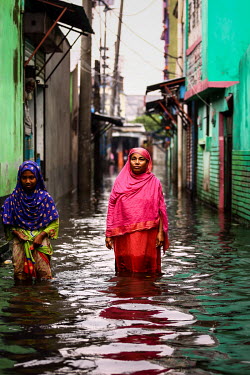 A woman wades along a street through knee deep flood water.  Water is essential for survival, yet in Bangladesh water also has the power to destroy anything in its path. For months at a time, monsoon...