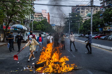 A flashmob of young anti-coup protestors burn tires and rubbish on the main road while security forces clear other roadblocks and patrol inside their neighbourhood, in Tamwe township.