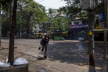 An anti-coup protestor runs as security forces raid into a neighbourhood in Tamwe township.