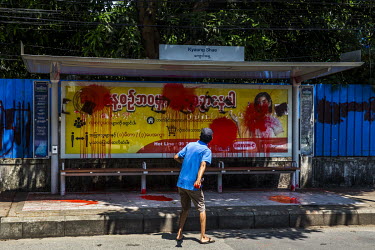 An anti-coup activist sprays red paint at a bus stop as part of the 'Red Campaign' to protest against the military coup in Tamwe township.
