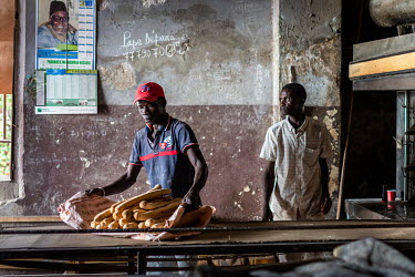 Atsff with freshly baked baguettes in Mathurin Ndiaye's bakery that his father founded in 1974. Now, 45 years later, he and his brothers manage it and sell about 2,000 sticks a day to individuals, hot...
