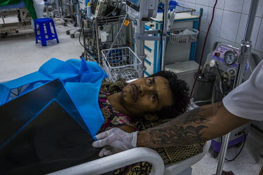 A man from Thanlyin township, with a gunshot wound, waits to get treated inside an emergency ward at a hospital where medical doctors and volunteer medics discreetly treat injured protestors and civil...