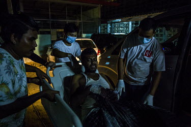 A man with a gunshout wound in the leg, shot during the protest crackdowns in Thanlyan township, arrives at the emergency ward at a hospital where a group of government medical officers participating...