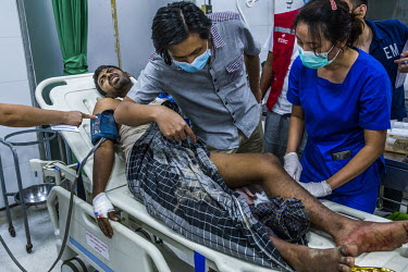 Medical doctors and volunteer medics check a man with a gunshot wound in the leg, shot during the protest crackdowns in Thanlyin township, at the emergency ward at a hospital where a group of governme...