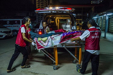 Volunteer medics carry an injured protestor, Hein Htet Aung (22), who has wounds to the face believed to be from a gunshot fired by the soldiers who raided his neighbourhood in Tharketa past midnight,...