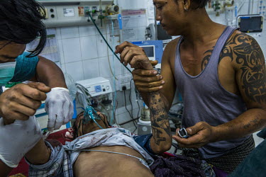 An injured protestor, Hein Htet Aung (22), who has wounds to the face believed to be from a gunshot fired by soldiers who raided his neighbourhood in Tharketa past midnight, is treated in the emergenc...
