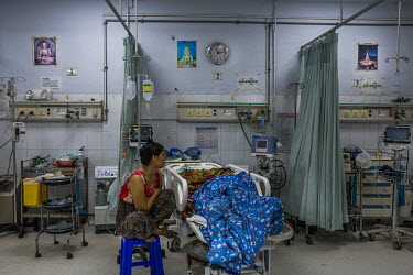Ma Khin Khin Oo, the mother of Hein Htet Aung (22), an injured protestor from Tharketa township who was wounded as soldiers fired live rounds while raiding the neighbourhood past midnight, sits with h...