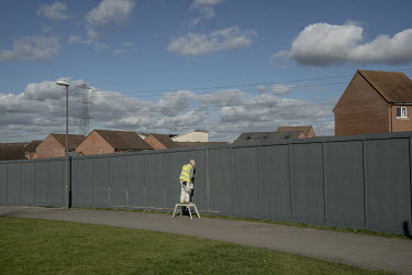 A workman paints a fence surrounding a new housing development on the edge of Aylesbury, close to the route of the HS2 high speed rail link.