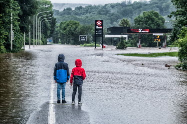 Two children stand on a flooded road looking towards a petrol station that has been inundated by water. Heavy rain caused the River Lomme to burst its banks resulting in widespread flooding in the pro...