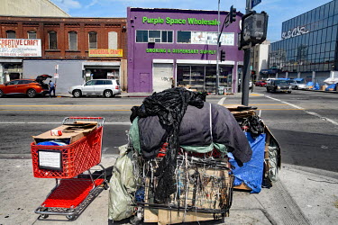 A homeless person's shelter and belongings on a pavement opposite the 'Purple Space Wholesale smoking and dispensary supply'.  Thousands of homeless people camp out in the centre of Los Angeles, in an...