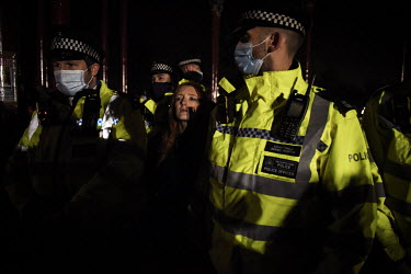 Police, citing COVID-19 lockdown regulations, detain a young woman as they begin a series of arrests of young people as they attempted to break up a vigil held at the bandstand on Clapham Common, wher...