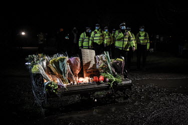 Police walk past a memorial for Sarah Everard after they attempted to break up a vigil, citing COVID-19 lockdown regulations, held at the bandstand on Clapham Common, where a large crowd of mostly wom...