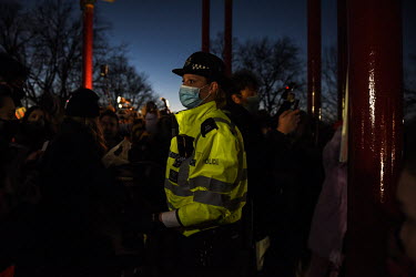 A female officer looks on as police, citing COVID-19 lockdown regulations, begin to crackdown on and try to get people to leave the area during a vigil at the bandstand on Clapham Common, close to whe...