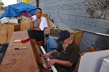 Nancy, a homeless person originally from from Missouri, smokes while Rodney, a man from Ohio who used to be a prtofessional musician, plays Hotel California on a discarded piano.  Thousands of homeles...