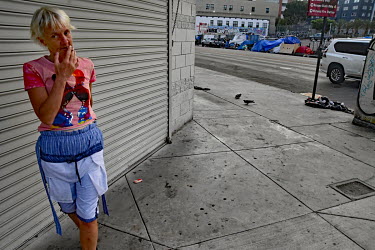 A homeless woman smokes a on a street corner.  Thousands of homeless people camp out in the centre of Los Angeles, in an area of about 50 blocks. In greater Los Angeles, there are 70,000 homeless peop...